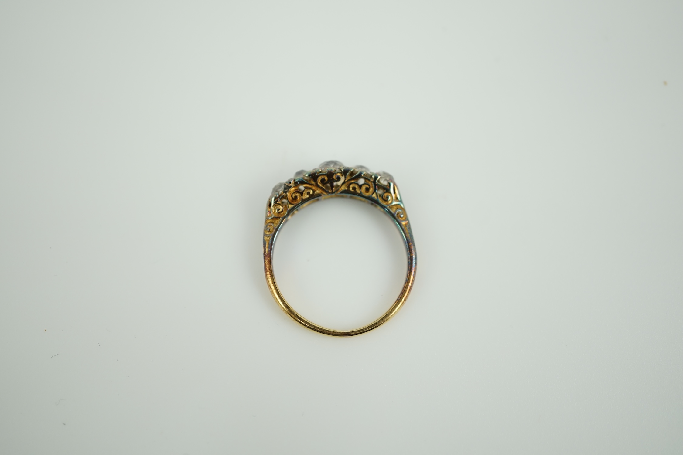 An early 20th century yellow metal and graduated five stone old round cut diamond set half hoop ring, with diamond chip spacers, size K, gross weight 2.8 grams.